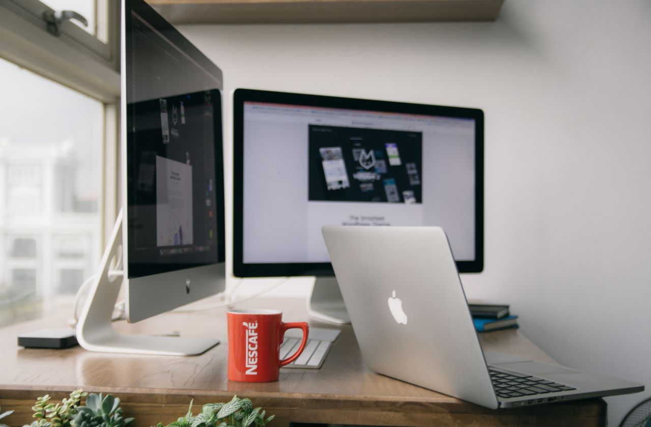 team-01 A bright modern office setup with computers and a mug on a desk.